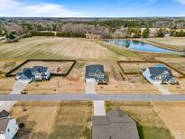 Expansive aerial view of charming homes near a serene lake and wooded area at 6804 Arlington Oaks Trl, Raleigh, NC 27603
