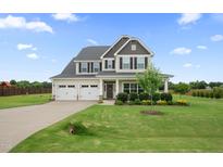 Charming two-story home with a well-manicured lawn, a three-car garage, and beautiful landscaping at 6804 Arlington Oaks Trl, Raleigh, NC 27603