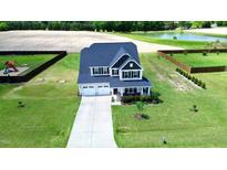 Expansive view of the two-story home showcasing its manicured lawn, two-car garage, and charming front porch at 6804 Arlington Oaks Trl, Raleigh, NC 27603