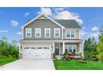 Charming two-story home featuring a two-car garage, landscaped yard, and covered front entry at 1032 Country Pasture Cv, Wendell, NC 27591