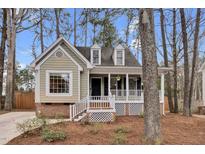Charming home featuring dormer windows, a cozy front porch, and a well-maintained yard with mature trees at 107 Fishers Creek Ct, Cary, NC 27513