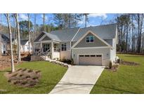 Charming single-Gathering home boasting beautiful gray siding, a well-manicured lawn, and a convenient two-car garage at 112 Rawhide Dr, Louisburg, NC 27549