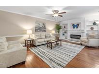 Cozy living room with a fireplace, ceiling fan, plush seating, and stylish decor at 228 Finley Forest Dr, Chapel Hill, NC 27517