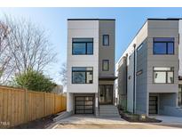 Modern three-story home featuring a clean, contemporary design with large windows and a glass garage door at 228 Woodsborough Pl, Raleigh, NC 27601