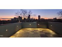 Stunning rooftop deck with pavers and a cityscape view at sunset at 228 Woodsborough Pl, Raleigh, NC 27601