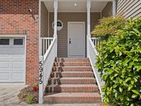 Inviting home entrance with brick steps, white railings, and a charming front door at 5945 Four Townes Ln, Raleigh, NC 27616