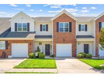 Charming townhouse with brick and siding exterior, well-maintained lawn, and attached garage on a sunny day at 622 Village Lake Drive, Mebane, NC 27302