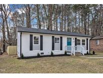 Charming single-story home featuring a freshly painted exterior, black shutters, and a cheerful blue front door at 838 Waring St, Durham, NC 27704