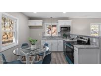 Bright kitchen features stainless appliances, light grey backsplash, and a glass table with blue chairs at 838 Waring St, Durham, NC 27704