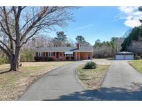 Charming brick home with a well-maintained lawn, a long driveway, and a detached garage at 8604 N Roxboro St, Bahama, NC 27503
