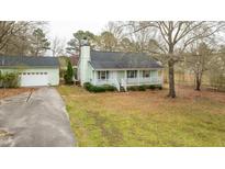 Charming single-story home featuring a covered front porch, green exterior, and detached garage at 879 Cheves Rd, Zebulon, NC 27597