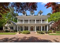 Stately home with a large front porch, dormer windows, and a well-manicured lawn and circular brick driveway at 109 Chimeneas Pl, Chapel Hill, NC 27517