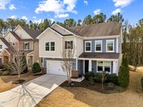 Charming two-story home with a manicured lawn, attached garage, and blue and cream colored facade at 1708 Capstone Dr, Durham, NC 27713
