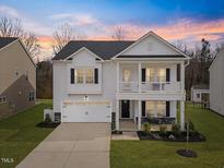 Charming two-story home featuring a welcoming front porch and attached garage with a beautiful sunset backdrop at 213 Chateau Way, Angier, NC 27501