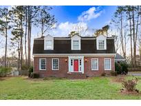 Charming brick home featuring a bright red front door and three dormer windows at 3836 Gloucester Rd, Rocky Mount, NC 27803