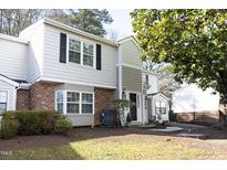 Charming townhome featuring a brick facade, large windows, and manicured landscaping at 7736 Falcon Rest Cir, Raleigh, NC 27615
