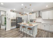 Bright kitchen features a large island with seating, stainless steel appliances, and white cabinets at 824 Wrights Creek Way, Wake Forest, NC 27587