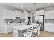 Bright kitchen features white cabinets, stainless steel appliances and island with bar stool seating at 90 Rigsby Ave, Four Oaks, NC 27524