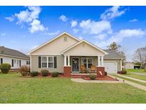 Charming home featuring a cozy front porch with rocking chairs, a well-manicured lawn, and delightful curb appeal at 112 E Main St, Micro, NC 27555
