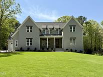 Charming two-story home boasts a manicured lawn and welcoming front porch, showcasing classic architectural details and curb appeal at 1405 Song Bird Crest Way, Raleigh, NC 27613