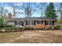 Charming one-story brick home featuring black shutters, manicured landscaping, and a cozy front porch at 303 Granville Rd, Chapel Hill, NC 27514