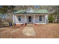 Charming single-story home featuring a covered front porch, set against a backdrop of mature trees at 404 Cherry St, Oxford, NC 27565