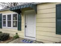 Charming home entrance featuring a white door, matching trim, and complementary green awning and shutters at 510 Short W St, Hillsborough, NC 27278