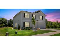 Charming two-story home with a manicured lawn and inviting curb appeal at dusk at 10 Forest Brook Way, Clayton, NC 27520