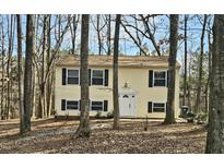 Charming two-story house with light yellow siding and black shutters surrounded by trees at 325 Bainbridge Cir, Garner, NC 27529