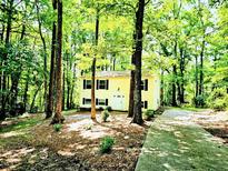 Charming yellow two-story home surrounded by lush trees and greenery, providing a serene and private setting at 325 Bainbridge Cir, Garner, NC 27529