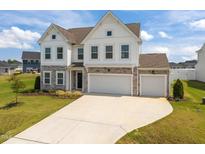 Beautiful two-story home with a three-car garage, stone accents, white siding, and manicured lawn at 350 Arlie Ln, Lillington, NC 27546