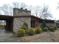Charming single-story brick home with mature landscaping and covered carport at 410 W Barrington St, Dunn, NC 28334