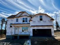 Under construction home featuring a two-car garage and a classic two-story design covered with Tyvek HomeWrap at 48 Golden View Pl, Zebulon, NC 27597