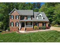 Stunning two-story red brick home with manicured lawn and lush landscaping at 5008 Sunset Forest Cir, Holly Springs, NC 27540