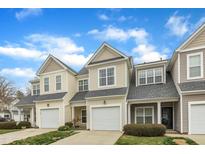 View of the townhome exteriors showing garages, front doors and landscaped lawns under a beautiful blue sky at 7246 Aquinas Avenue Ave, Raleigh, NC 27617