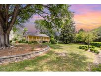 Charming home with covered porch, stone wall feature, and mature trees in a spacious front yard at 8324 Humie Olive Rd, Apex, NC 27502