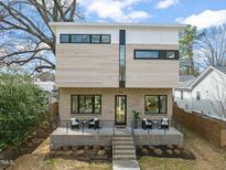 Modern home with brick and wood exterior, black framed windows, and inviting front porch seating at 909 Iredell St, Durham, NC 27705