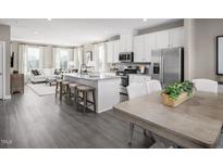 Open-concept kitchen features a large island with seating and stainless steel appliances, flowing into a cozy living area at 1364 Chowan Ave, Durham, NC 27713
