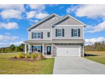 Charming two-story home featuring a gray exterior, stone accents, and an attached two-car garage at 19 Double Barrel St, Lillington, NC 27546