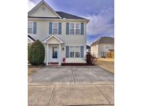 Charming townhome featuring light yellow siding and blue shutters, with a concrete driveway and tidy landscaping at 2323 Turtle Point Dr, Raleigh, NC 27604