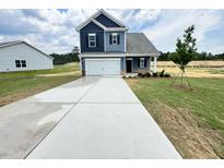 Charming two-story home with a well-manicured lawn and a long driveway leading to an attached garage at 253 Deodora Ln, Cameron, NC 28326