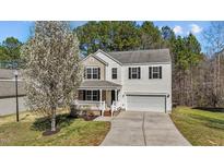 Charming two-story home with a well-maintained lawn, a blooming tree, and an inviting front porch at 264 Farrington Dr, Clayton, NC 27520