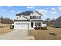 Two-story home with a two-car garage, white brick facade, and manicured front lawn at 277 Martins Mill Ct, Wendell, NC 27591