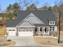 Charming two-story home with stone accents, a covered porch, and a two-car garage at 33 Song Breeze Cir, Angier, NC 27501