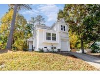Charming two-story home featuring a well-manicured lawn and a classic white exterior nestled among mature trees at 460 Dickens Dr, Raleigh, NC 27610