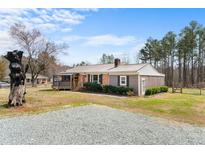 Charming single story home with a metal roof, quaint porch, and gravel drive nestled in a wooded area at 492 Pixley Pritchard Rd, Timberlake, NC 27583