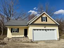 Charming yellow home featuring an attached white garage, stylish black shutters, and stone accents at 512 Hicksmill Rd, Oxford, NC 27565