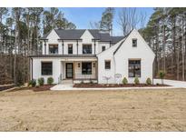 Striking two-story white brick home featuring black trim and a well-manicured lawn at 5213 Bent Leaf Dr, Raleigh, NC 27606