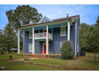 Charming two-story home features blue siding, red doors, and a quaint porch at 613 Mclean St, Spring Hope, NC 27882
