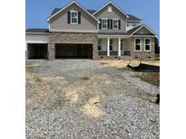 New two-story home featuring stone accents, a covered front porch, and an attached three-car garage at 72 Cultivator Ct, Angier, NC 27501